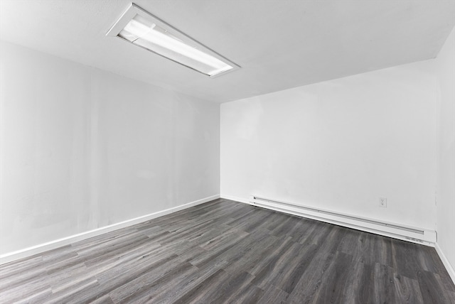 empty room with dark hardwood / wood-style floors and baseboard heating