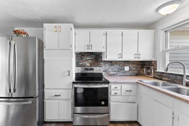 kitchen featuring hardwood / wood-style floors, white cabinets, stainless steel appliances, and sink