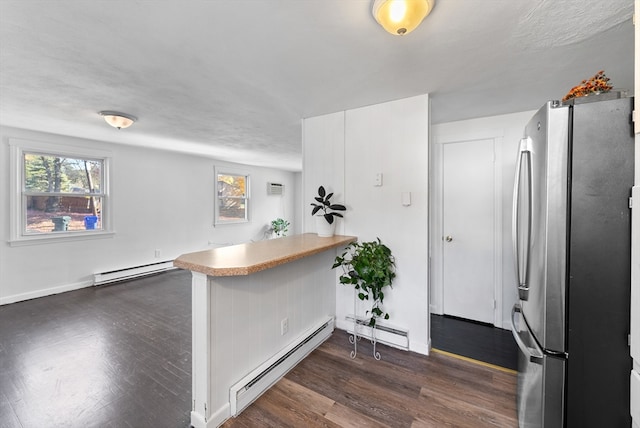 kitchen with kitchen peninsula, white cabinets, a baseboard radiator, stainless steel refrigerator, and dark wood-type flooring