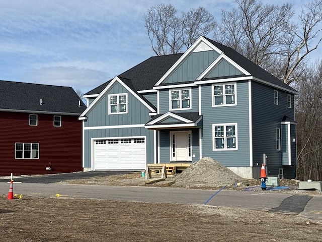 view of front of home featuring aphalt driveway, roof with shingles, board and batten siding, and an attached garage