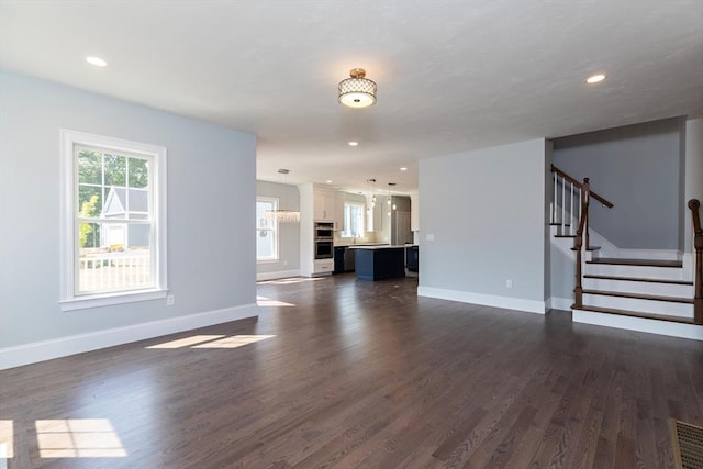 unfurnished living room featuring dark wood-style floors, stairway, recessed lighting, and baseboards