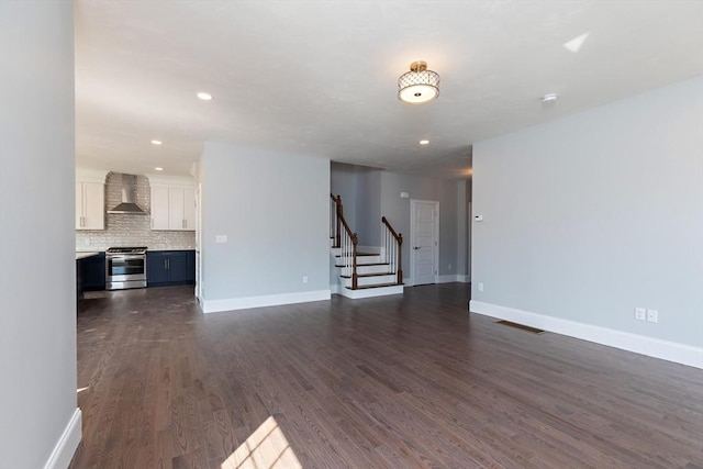 unfurnished living room with stairway, visible vents, dark wood-style flooring, and baseboards