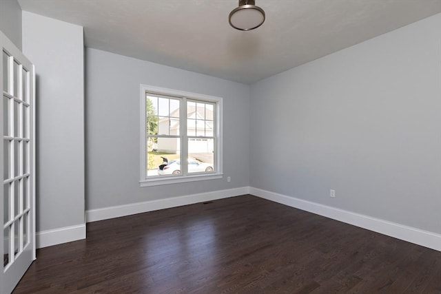 unfurnished room featuring baseboards and dark wood-style flooring