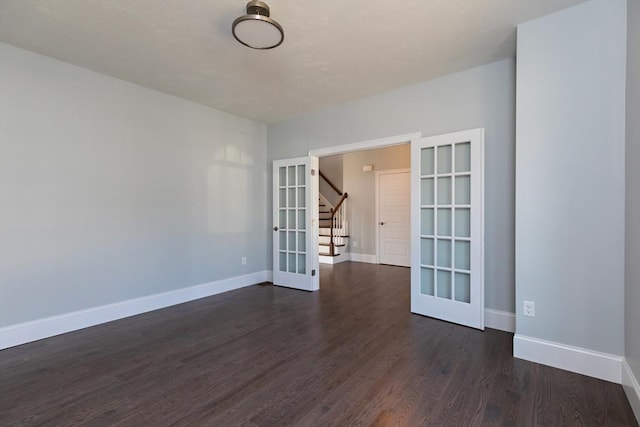 empty room featuring dark wood-style floors, french doors, and baseboards