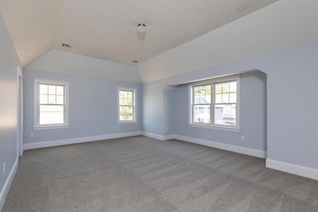 spare room with visible vents, baseboards, carpet, and vaulted ceiling