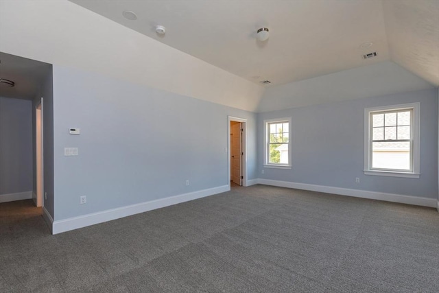 unfurnished room with lofted ceiling, visible vents, baseboards, and dark colored carpet