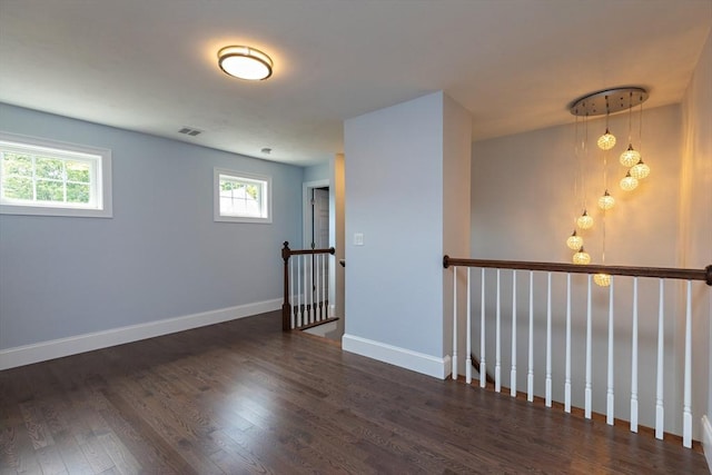 unfurnished room featuring visible vents, wood finished floors, and baseboards