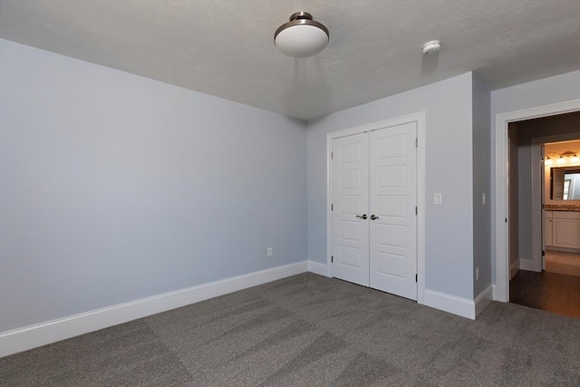 unfurnished bedroom with a closet, dark carpet, and baseboards