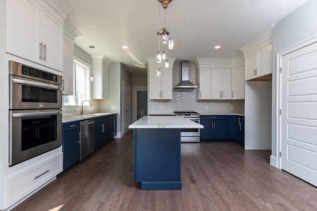 kitchen featuring blue cabinetry, stainless steel appliances, white cabinetry, and wall chimney range hood