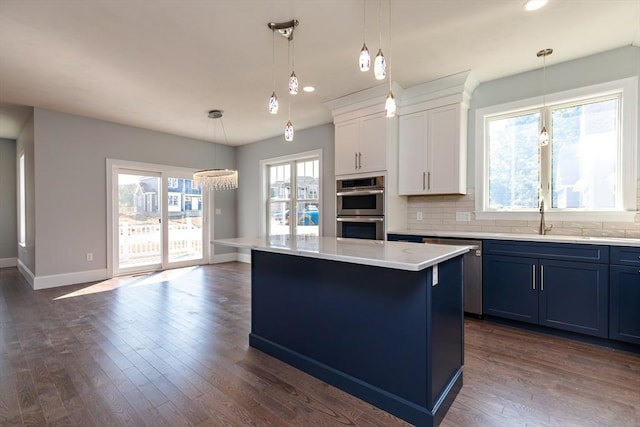 kitchen with blue cabinets, a kitchen island, tasteful backsplash, stainless steel appliances, and light countertops