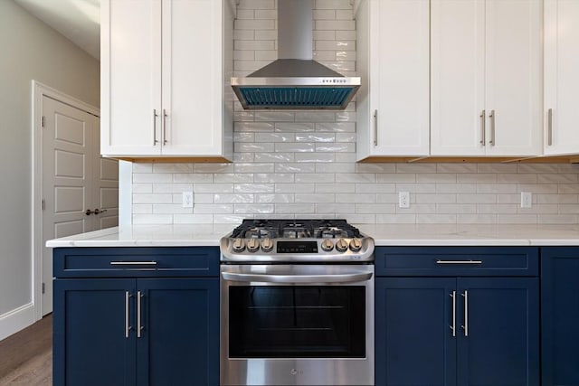 kitchen featuring gas stove, blue cabinets, tasteful backsplash, and wall chimney exhaust hood