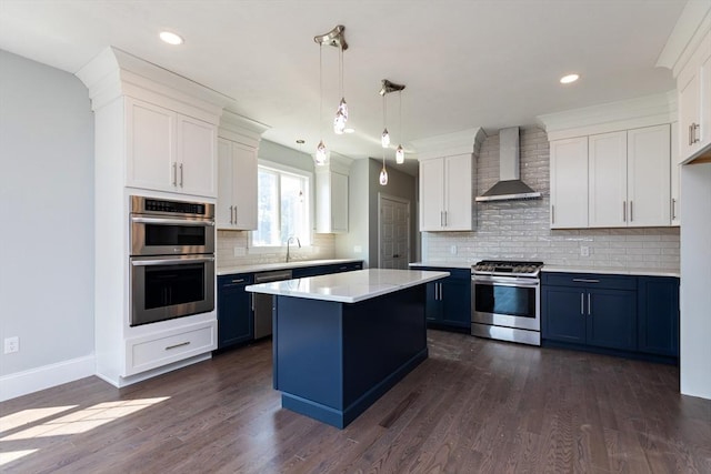 kitchen featuring wall chimney range hood, dark wood-style floors, stainless steel appliances, white cabinets, and light countertops