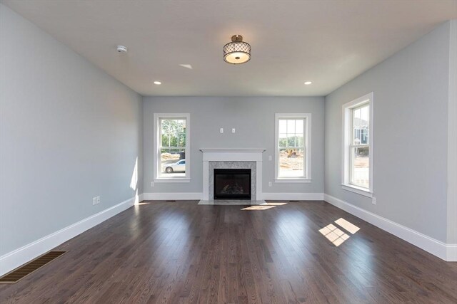 unfurnished living room featuring visible vents, baseboards, and dark wood-type flooring