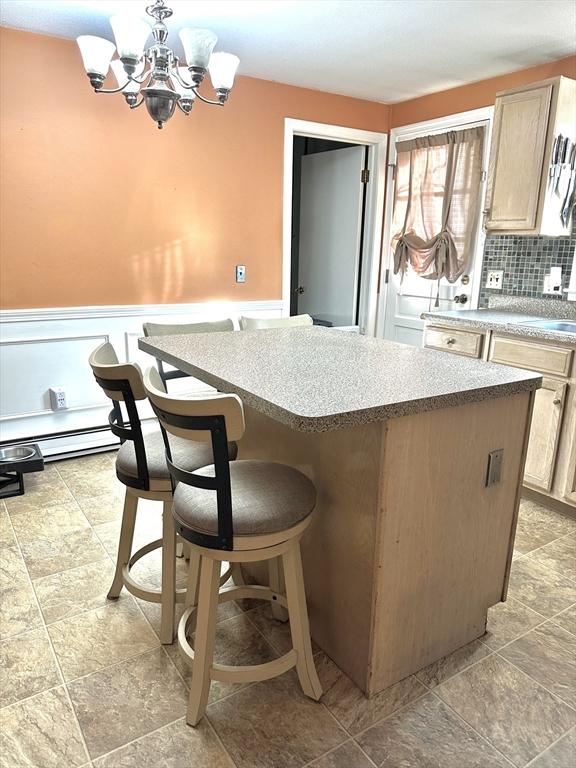 kitchen featuring tasteful backsplash, light brown cabinets, a chandelier, a center island, and a breakfast bar area