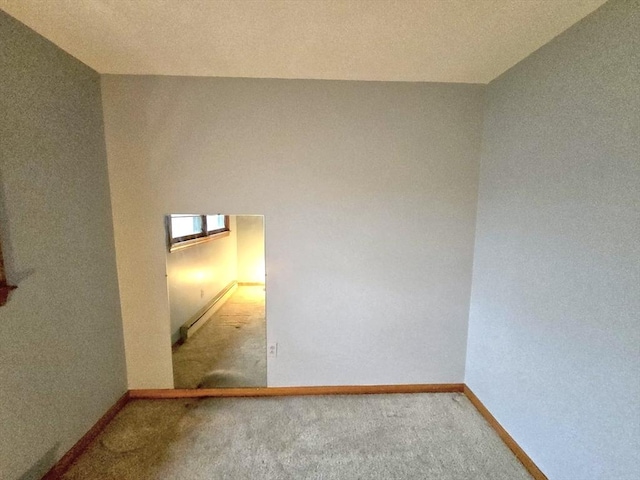 unfurnished room featuring carpet floors and a baseboard heating unit