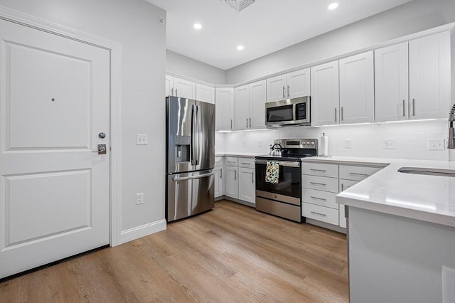 3302 Briarwood Vlg Unit 3302, Clinton, MA 01510 - kitchen featuring stainless steel appliances, decorative backsplash, white cabinetry, light wood-style floors, and light countertops