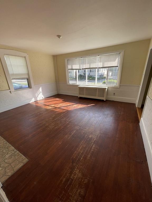 empty room with radiator and dark wood-style flooring