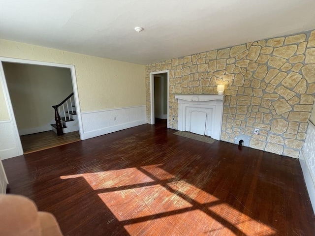 unfurnished living room featuring wood-type flooring, stairway, and a fireplace with flush hearth