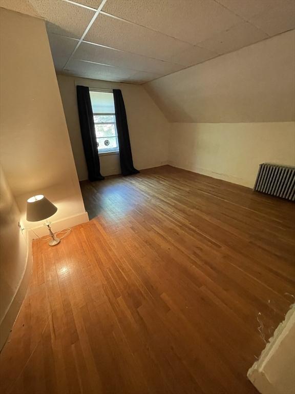 bonus room featuring wood finished floors, lofted ceiling, baseboards, and radiator