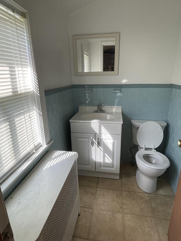 bathroom featuring tile walls, toilet, wainscoting, and vanity