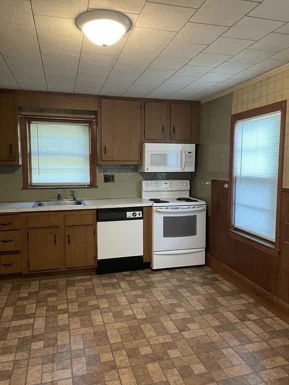 kitchen with white appliances, brick patterned floors, a sink, light countertops, and baseboards