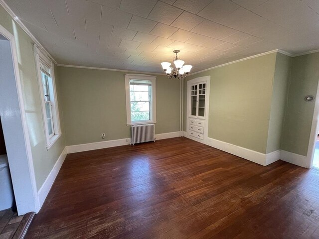 spare room with radiator, ornamental molding, a chandelier, dark wood finished floors, and baseboards