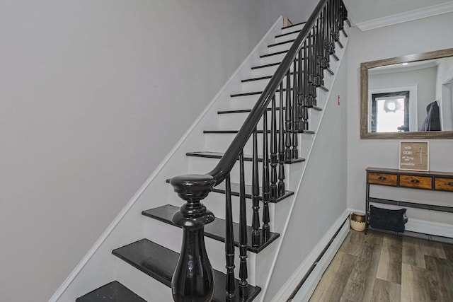 stairs with baseboard heating, crown molding, and hardwood / wood-style floors