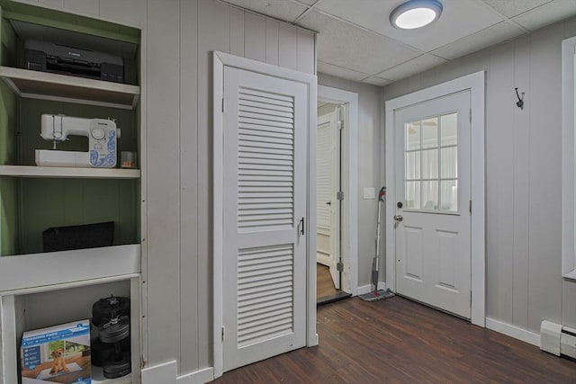 entryway with baseboard heating, dark hardwood / wood-style flooring, a paneled ceiling, and built in shelves