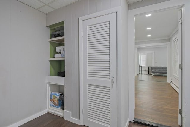 interior space featuring baseboard heating, a drop ceiling, and wood-type flooring