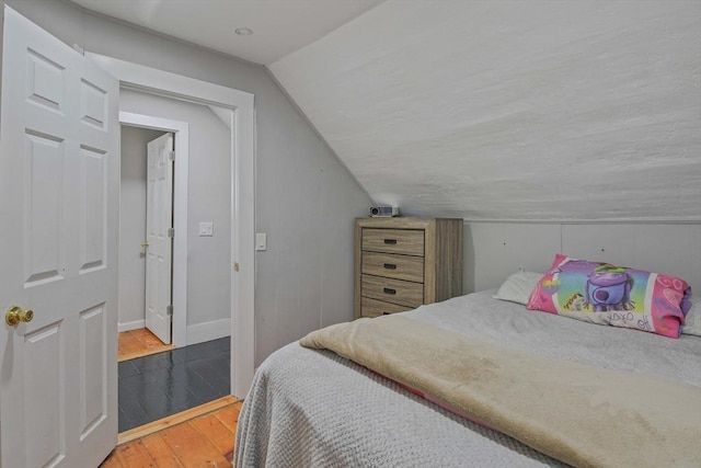 bedroom with vaulted ceiling and wood-type flooring