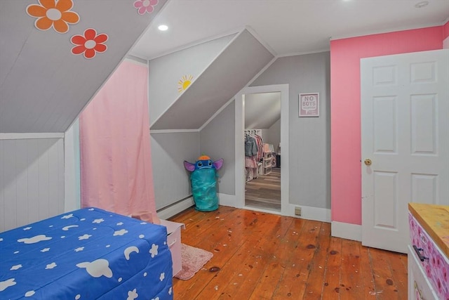 bedroom with vaulted ceiling, wood-type flooring, and a baseboard heating unit