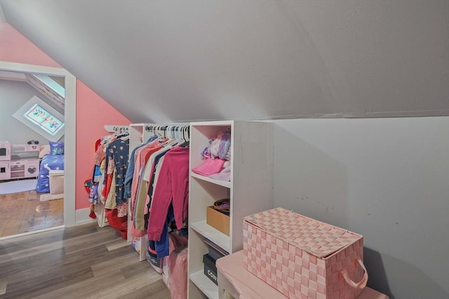 walk in closet with hardwood / wood-style flooring and vaulted ceiling