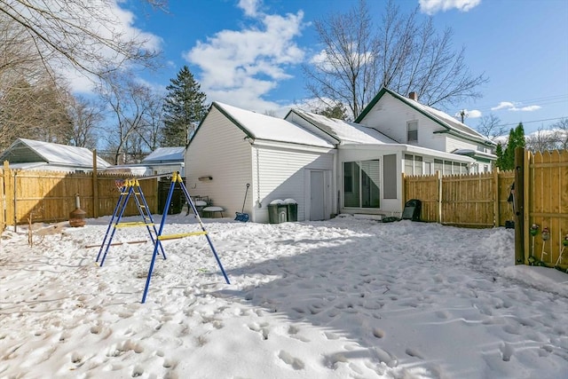 snow covered rear of property with a playground