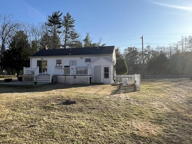 rear view of house featuring a yard, a deck, and fence