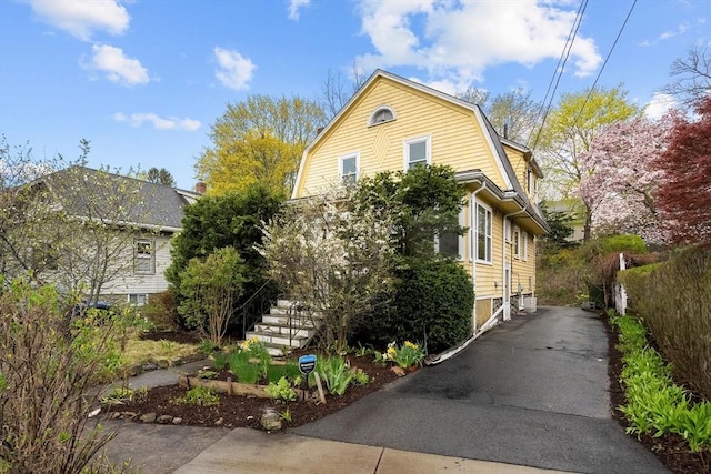 view of front of house featuring fence, a gambrel roof, and aphalt driveway