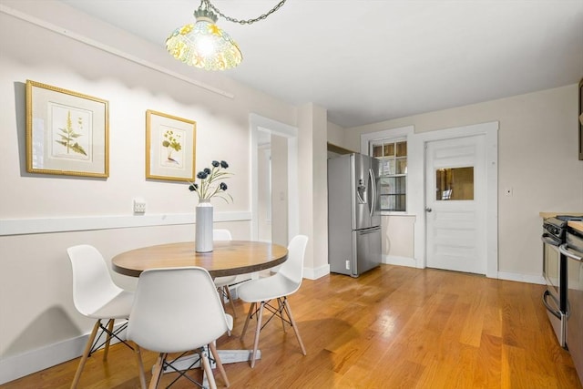 dining area featuring light wood-type flooring and baseboards
