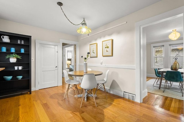 dining space featuring visible vents, light wood-style flooring, and baseboards