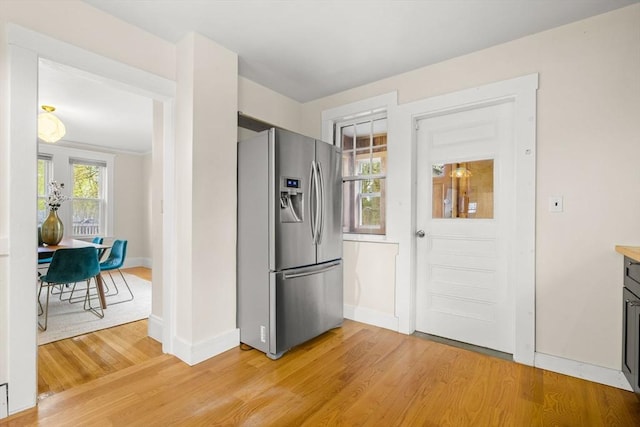 kitchen featuring light countertops, baseboards, stainless steel fridge, and light wood finished floors