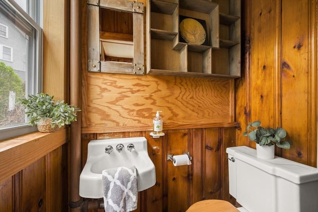 bathroom featuring wooden walls and toilet