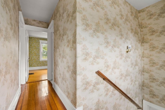 corridor featuring baseboards, visible vents, hardwood / wood-style flooring, and wallpapered walls