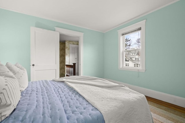 bedroom featuring baseboards, ornamental molding, and wood finished floors