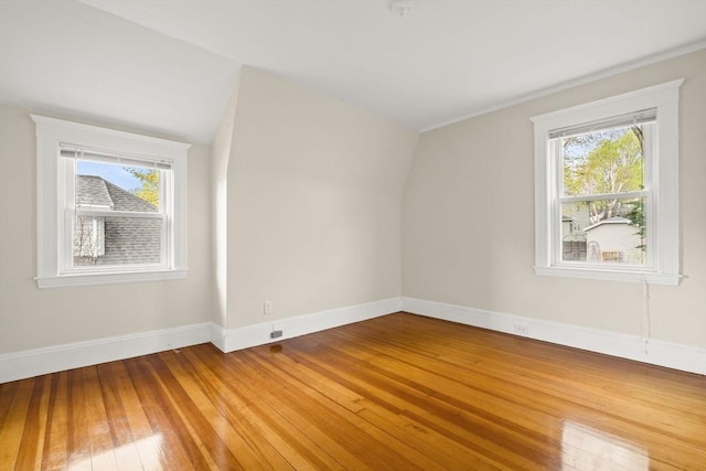 additional living space with baseboards, a healthy amount of sunlight, and light wood-style floors