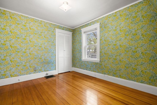 spare room with baseboards, ornamental molding, wood-type flooring, and visible vents