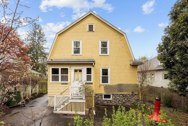 rear view of house featuring a patio, a gambrel roof, and fence