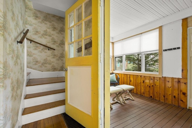 stairway featuring wood walls, wainscoting, hardwood / wood-style flooring, and wallpapered walls