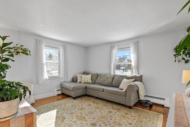 living area with a wealth of natural light, baseboard heating, and wood finished floors