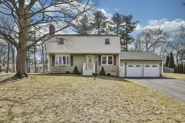 colonial-style house with driveway, fence, a front yard, a garage, and a chimney