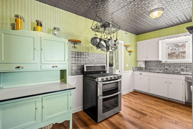 kitchen featuring hardwood / wood-style flooring, white cabinetry, sink, and gas range