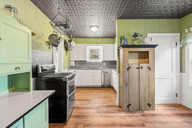 kitchen featuring sink, backsplash, light hardwood / wood-style floors, white cabinets, and appliances with stainless steel finishes