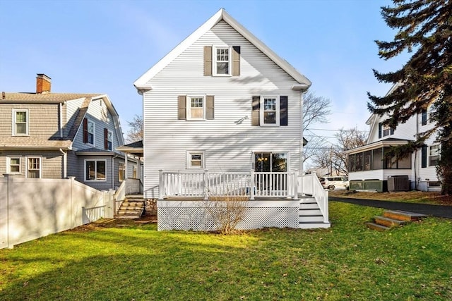 rear view of house with central AC, a sunroom, a deck, and a lawn